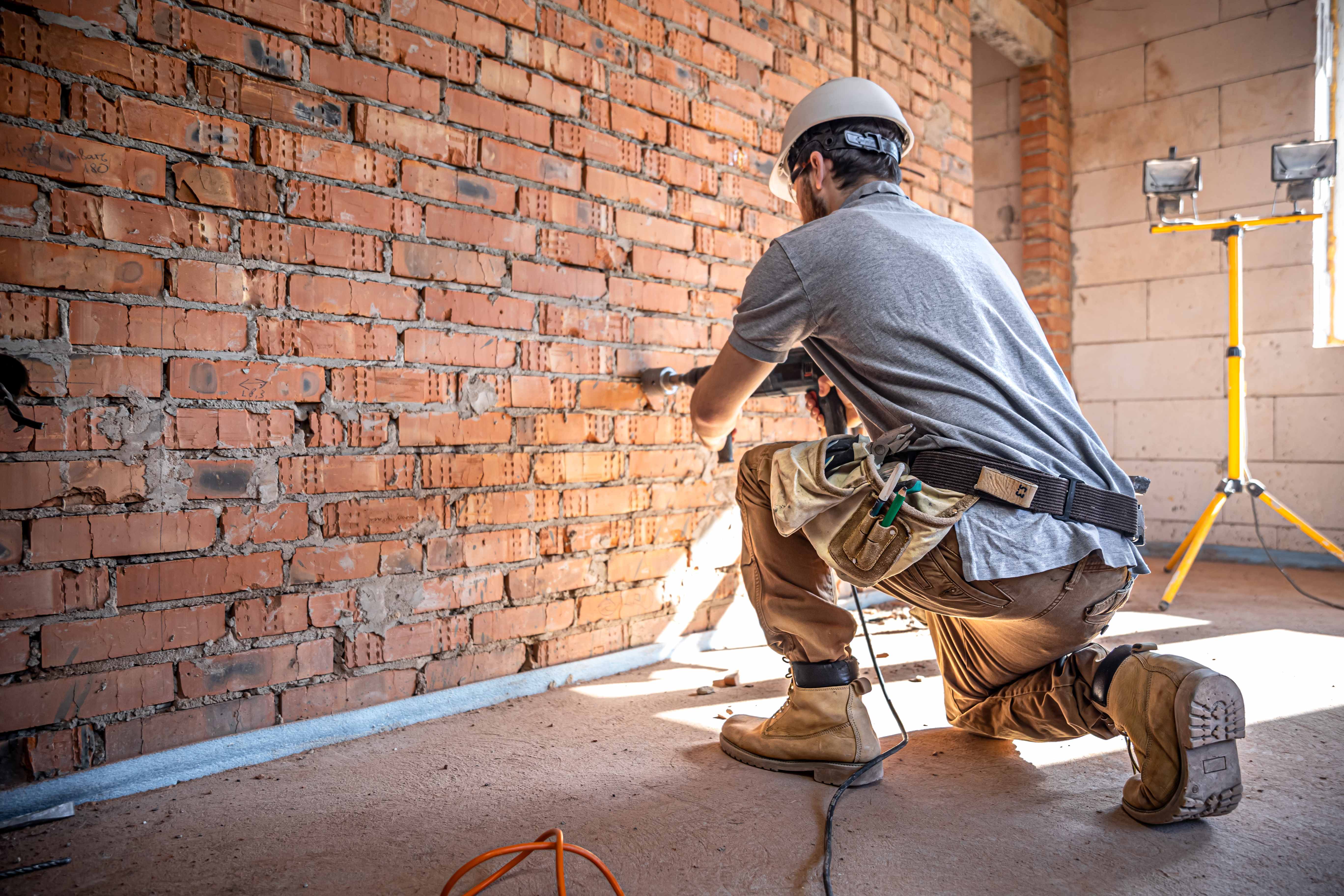 Profissional perfurando parede em obra - Serviços construção civil RJ